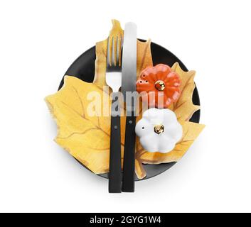 Table de Thanksgiving avec salières et poivriers de citrouille, couverts et feuille d'arbre en papier sur fond blanc Banque D'Images