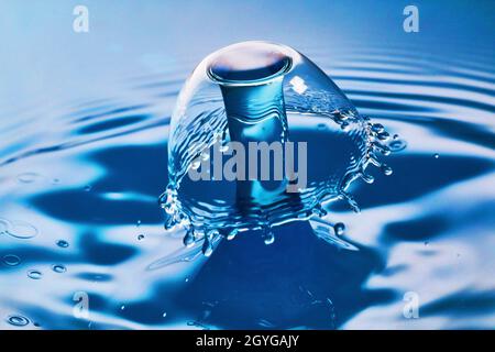 Collision de deux gouttes d'eau sur l'eau bleue avec des ondulations Banque D'Images