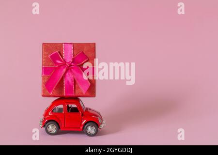 01.10.2021-Zavyalovo, Russie.Une petite voiture rétro en métal rouge avec une boîte cadeau.le concept de la livraison de cadeau Banque D'Images