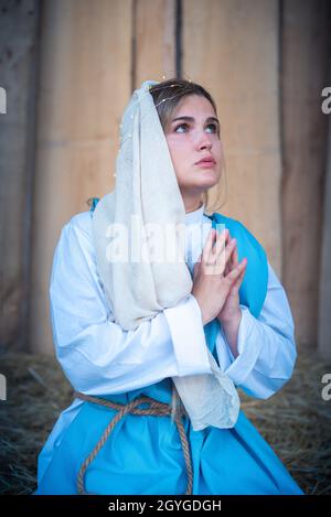 Femme caucasienne représentant la Vierge marie en priant dans un berceau Banque D'Images