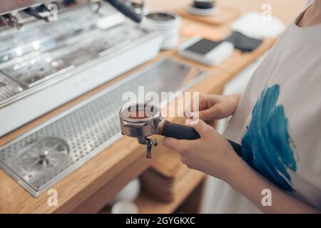 Les mains du barista féminin tiennent le porte-filtre avec du café moulu frais Banque D'Images