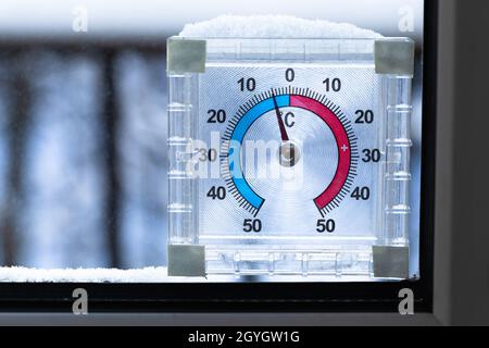 Le thermomètre de fenêtre extérieur recouvert de neige indique une température négative en degrés Celsius.Gros plan avec mise au point sélective Banque D'Images