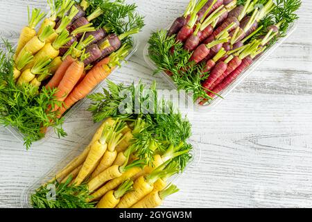 Mini carottes colorées fraîchement récoltées sur fond blanc en bois Banque D'Images