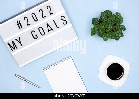 Plans pour le concept de 2022 ans à venir.Bloc-notes, stylo, tasse à café, visionneuse avec texte Mes objectifs sur un bureau bleu.Un lieu de travail soigné Banque D'Images
