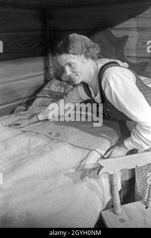 Auf der Landwirtschafts- und Ernährungsausstellung "Grüne Woche' à Berlin zeigt eine Frau selbstgenähte Bettwäsche, Deutschland 1930 er Jahre. Au agricultural trade show 'Gruene Woche' à Berlin une femme montrant l'auto cousu le linge de lit, de l'Allemagne des années 1930. Banque D'Images