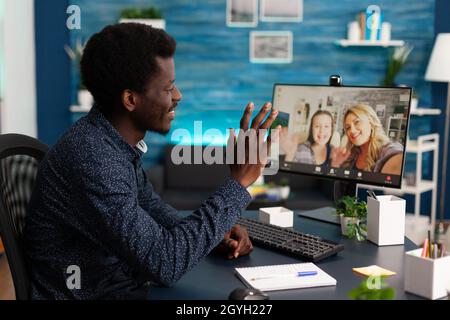 Homme étudiant saluant des amis distants profitant de temps libre pendant la conférence de réunion vidéo en ligne dans le salon.Adolescent discutant d'un projet scolaire, appel de télétravail par vidéoconférence sur écran d'ordinateur Banque D'Images