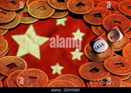 Le drapeau de la Chine entouré de pièces de monnaie feng shui.Dés avec les mots VENDRE ACHETER sur les bords.Le concept d'investissement dans l'économie chinoise. Banque D'Images