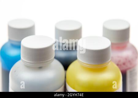 Cinq flacons en plastique avec différentes encres pour imprimante à jet d'encre sur fond clair Banque D'Images