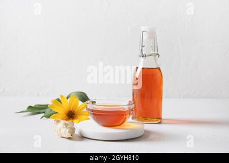 Sirop d'artichaut topinambour en bouteille, fleurs et racine sur fond blanc.Copier l'espace. Banque D'Images