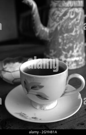 Gros plan vertical en niveaux de gris d'une tasse et d'une soucoupe avec du thé Banque D'Images