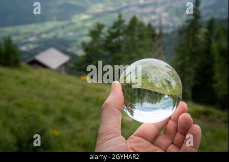 Main tenant la sphère de verre devant le pâturage, jour nuageux en été, alpes dans le Tyrol oriental (Autriche) Banque D'Images