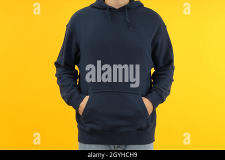 Homme à capuche avec les mains dans la poche sur fond jaune. Banque D'Images