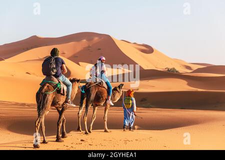 Les touristes en chameaux sont photographiés dans les dunes du désert du Sahara Banque D'Images