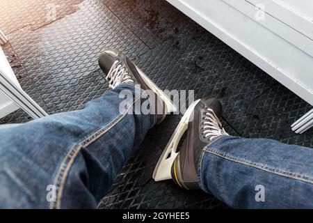 Vue rapprochée des jambes des hommes portant un Jean et des bottes noires de location sur un tapis souple en caoutchouc antidérapant dans le vestiaire Banque D'Images