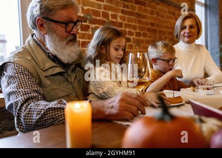 Petite fille mignonne, les enfants visitent les grands-parents et célèbrent le jour de Thanksgiving à la maison, à l'intérieur.Famille, concept de vacances. Banque D'Images