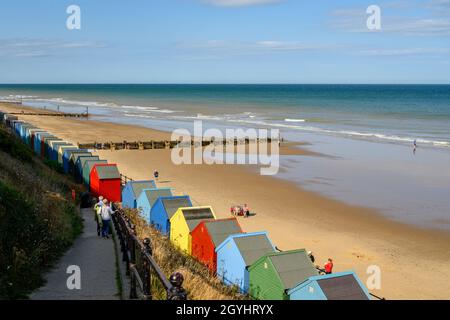 Une rangée de cabanes de plage peintes de couleurs vives sur la plage de Mundesley, Norfolk, Angleterre. Banque D'Images