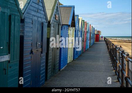 Une rangée de cabanes de plage peintes de couleurs vives sur la plage de Mundesley, Norfolk, Angleterre. Banque D'Images