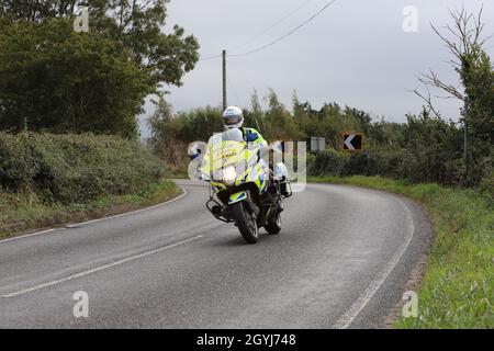 Une moto de police dans un virage sur une route de campagne dans l'Essex. L'officier fait partie d'une équipe qui déblayage la route avant une course à vélo. 'Course de cycle d'arrêt'. Banque D'Images