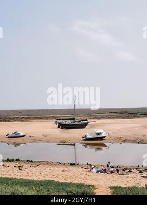 Bateaux à marée basse dans le paysage de marais d'été de Wells à côté de la mer sur la côte nord de Norfolk Heriritage à Norfolk Angleterre Royaume-Uni Banque D'Images