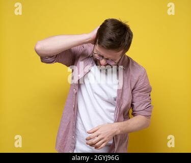 L'homme éprouve de graves douleurs à l'arrière de la tête ou du cou, il tient sur la zone enflammée avec la main et souffre. Banque D'Images