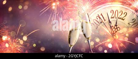 Célébration du nouvel an 2022 - compte à rebours et toast avec champagne et feux d'artifice sur le contexte flou artistique abstrait Banque D'Images