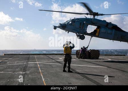 200108-N-GR168-1227 MER MÉDITERRANÉE (JANV8, 2020) Aviation Boatswain’s Mate (Handling) 3rd Class Lorenzo Moreno, centre, affecté au navire de transport amphibie de la classe San Antonio USS New York (LPD 21), dirige un hélicoptère MH-60S Sea Hawk, affecté aux baleines-dragons de l’Escadron de combat de la mer (HSC) 28,Alors que le compagnon de Boatswain (carburants) de l’aviation, 3e classe Stuart Price, à droite, et le compagnon de Boatswain (carburants) de l’aviation, Airman Tyler Strohl, tous deux affectés à New York, accrochent la cargaison au MH-60s lors d’un réapprovisionnement en mer, le 8 janvier 2020.New York, maison à Mayport, Floride, i Banque D'Images