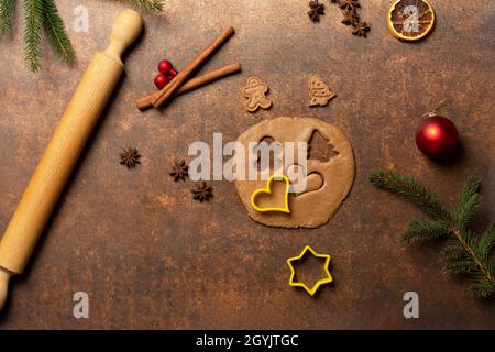 Pâte de pain d'épice, emporte-pièces, un homme de pain d'épice, un biscuit d'arbre de Noël, une broche roulante, une branche de sapin, des épices, des ornements d'arbre de Noël rouge... Banque D'Images