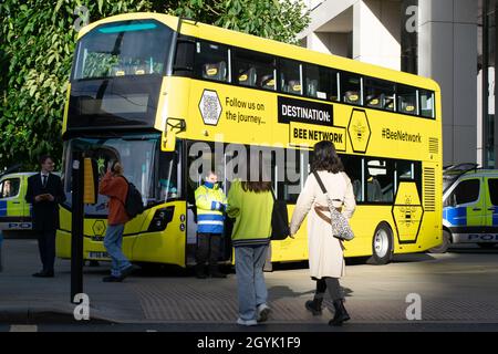 Bus jaune du réseau Bee planifié Manchester Royaume-Uni.Place Saint-Pierre pendant la Conférence du Parti conservateur.Véhicules de police en arrière-plan. Banque D'Images