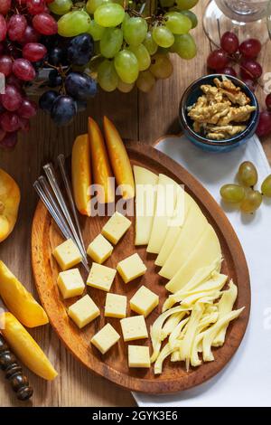 Un apéritif de différents types de fromage, raisins et noix, servi avec du vin. Style rustique. Banque D'Images