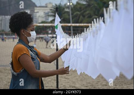 Rio de Janeiro, Brésil.08 octobre 2021.Une femme est suspendue à des mouchoirs blancs sur la plage de Copacabana lors d'une manifestation pour commémorer les personnes décédées de Covid-19 au Brésil.Près de 600,000 décès ont été enregistrés au Brésil.Credit: Andre Borges/dpa/Alamy Live News Banque D'Images