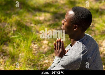 Relaxant homme afro-américain assis et méditant à la campagne Banque D'Images