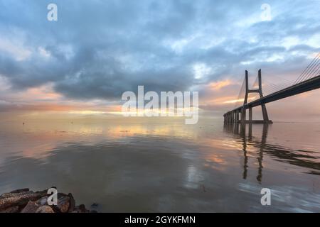 Arrière-plan avec lever de soleil coloré sur le pont de Lisbonne. Le pont Vasco da Gama est un point de repère et l'un des plus longs ponts du monde. réseau local urbain Banque D'Images