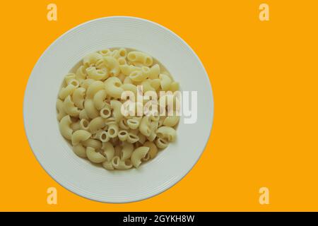 Vue de dessus Macaroni cuit sur plaque ronde blanche et le fond est jaune vif, espace de copie. Banque D'Images