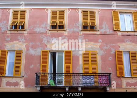 Ce bâtiment à la façade rose comprend un balcon et des fenêtres aux volets jaunes Banque D'Images