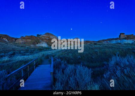 Jupiter (le plus lumineux) et Saturne (à droite) s'élevant dans le sud-est à Capricornus, au milieu du crépuscule nocturne de plus en plus intense sur les Badlands de Dinosaur Pr Banque D'Images