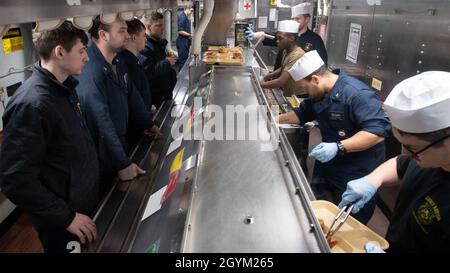 GOLFE PERSIQUE (janv25, 2020) - les marins affectés au destroyer à missiles guidés USS Carney (DDG 64) reçoivent de la nourriture des spécialistes culinaires lors du brunch, le 25 janvier 2020.Carney est déployé dans la zone d'opérations de la 5e flotte des États-Unis à l'appui des opérations navales afin d'assurer la stabilité et la sécurité maritimes dans la région centrale, reliant la Méditerranée et le Pacifique par l'océan Indien occidental et trois points d'étranglement stratégiques.(É.-U.Photo marine par le spécialiste des communications de masse 1ère classe Fred Gray IV) Banque D'Images