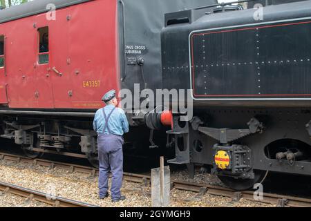 Sheringham, Norfolk, Royaume-Uni - SEPTEMBRE 14 2019 : l'exploitant de train en uniforme d'époque effectue des contrôles sur un train à vapeur Black BR Standard 4 76084 Banque D'Images