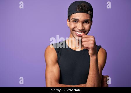 Portrait du jeune homme brunette souriant en t-shirt noir et casquette.Heureux modèle latino de trans genre Banque D'Images