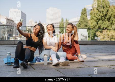 Jeunes femmes sportives attrayantes se reposer après l'entraînement ensemble et faire le selfie. Banque D'Images