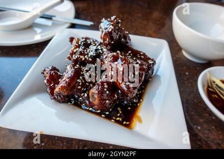 Gros plan des côtes de porc saucy sur une assiette carrée blanche à l'intérieur d'un restaurant asiatique Banque D'Images