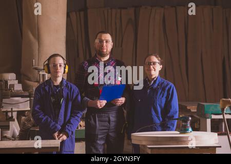 Famille de menuisiers gaie posant dans un atelier de travail du bois Banque D'Images