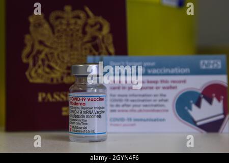 Dans cette illustration, un passeport britannique, une carte de vaccination Covid-19 et un flacon contenant le vaccin Moderna Covid-19 dans un centre de vaccination. Banque D'Images