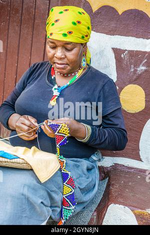 Johannesburg Afrique du Sud, Lesedi African Lodge & Cultural Village, Zulu Xhosa Pedi Basotho tribu Ndebele, Black Woman making perles collier Banque D'Images