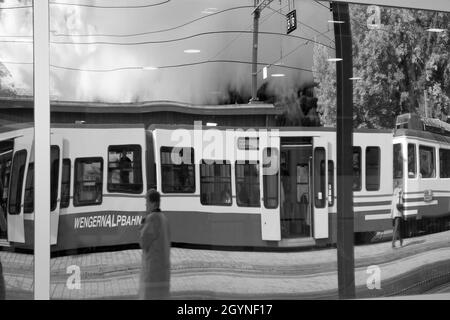 Gare de Wengen: Un train Wengernalpbahn en verre miroir, Oberland bernois, Suisse.Version noir et blanc. Banque D'Images