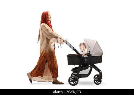 Photo pleine longueur d'une femme portant un hijab et poussant un bébé garçon dans une poussette isolée sur fond blanc Banque D'Images
