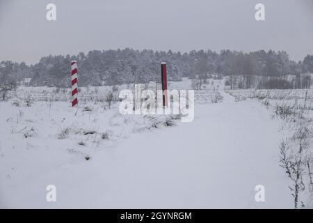 Les piliers limitrophes de la Biélorussie et de la Pologne à la frontière dans un champ d'hiver Banque D'Images