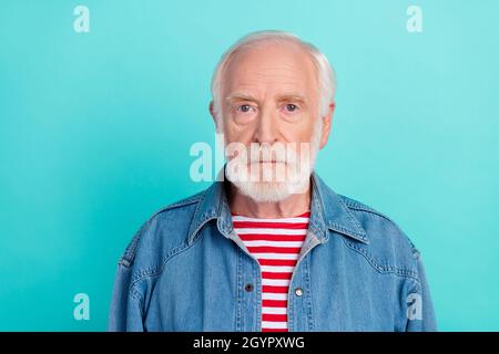 Portrait de contenu attrayant sérieux gris-cheveux d'âge moyen homme portant une veste en denim isolé sur fond bleu turquoise clair teal couleur Banque D'Images