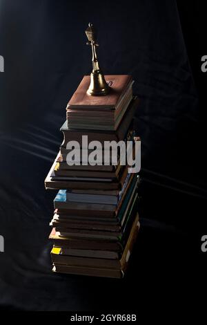 Photographie sombre et sinistre d'une pile de vieux livres anciens anciens sur fond noir foncé Banque D'Images