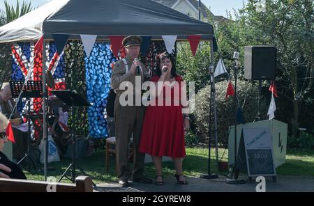 Sheringham, Norfolk, Royaume-Uni - SEPTEMBRE 14 2019 : homme en uniforme militaire des années 1940 et femme en robe rouge chantant pendant le week-end des années 1940 Banque D'Images