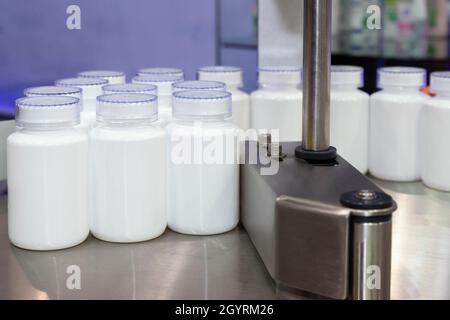 flacon en plastique blanc médical ou cosmétique sur la ligne de production du tapis transporteur au niveau de la machine de remplissage dans la fabrication de produits de santé. Banque D'Images